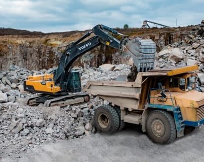 Екскаватор вантажить граніт у самоскид