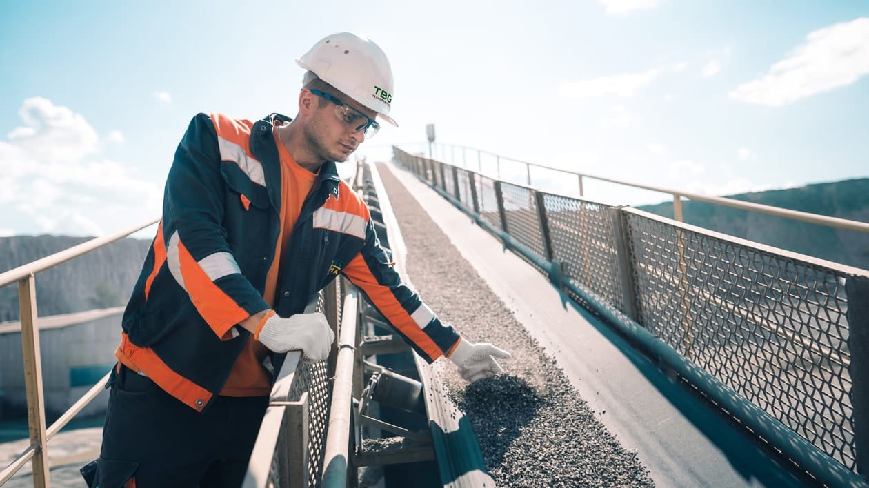 A worker at Klesiv quarry checks the quality of gravel on a conveyor belt