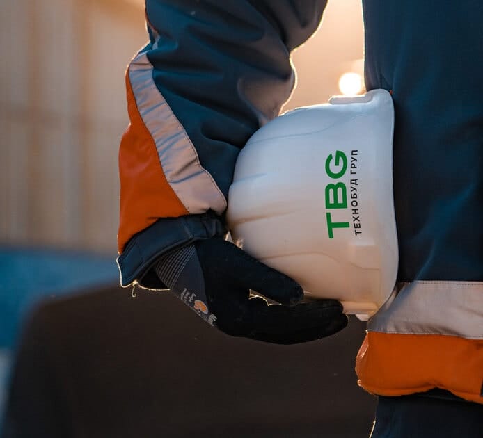 Працівник з робочою каскою Технобуд Груп в руках